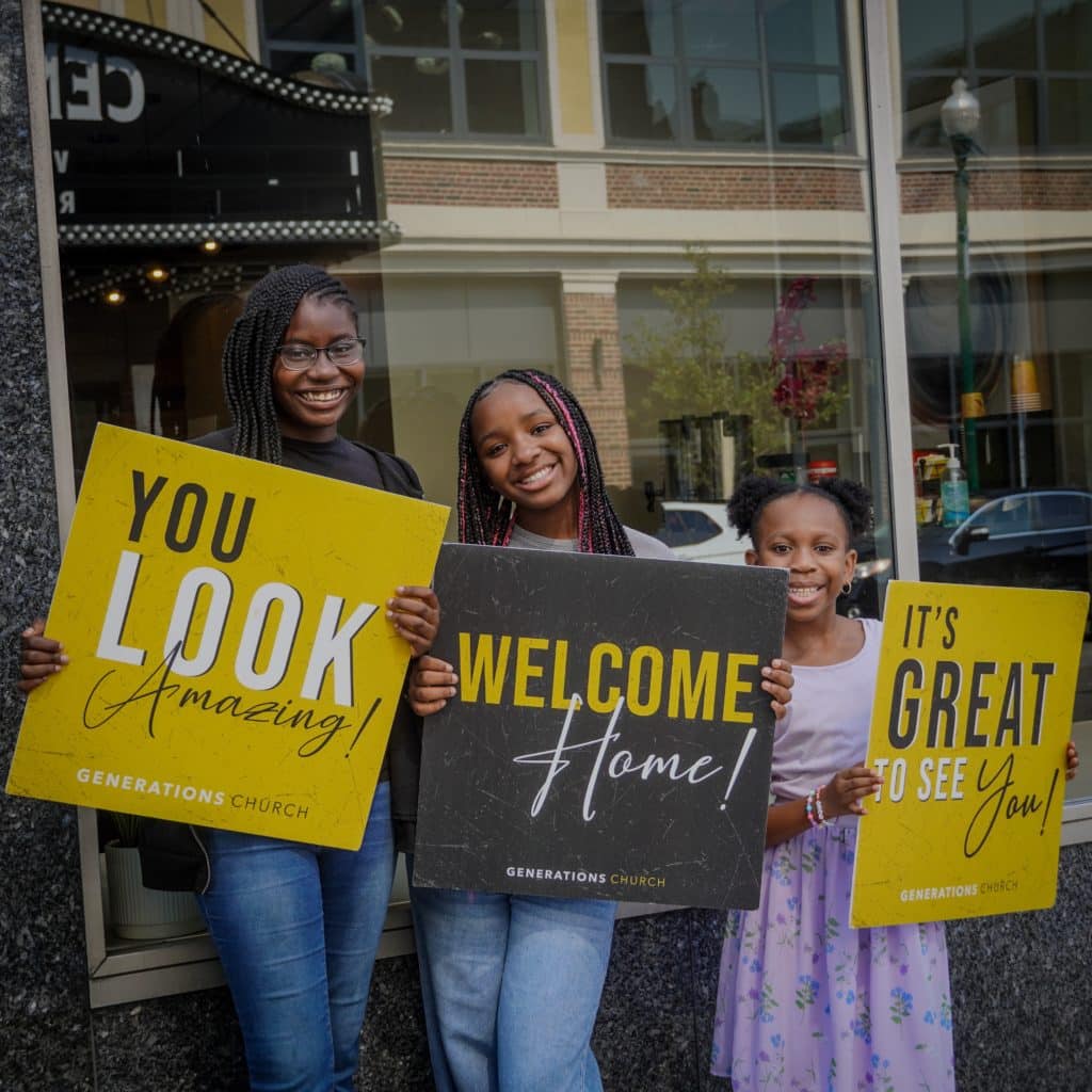 Three young girls greeting new guests at Generations Church