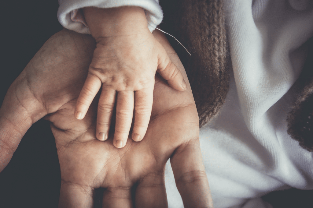 A father's hand hold his baby's hand