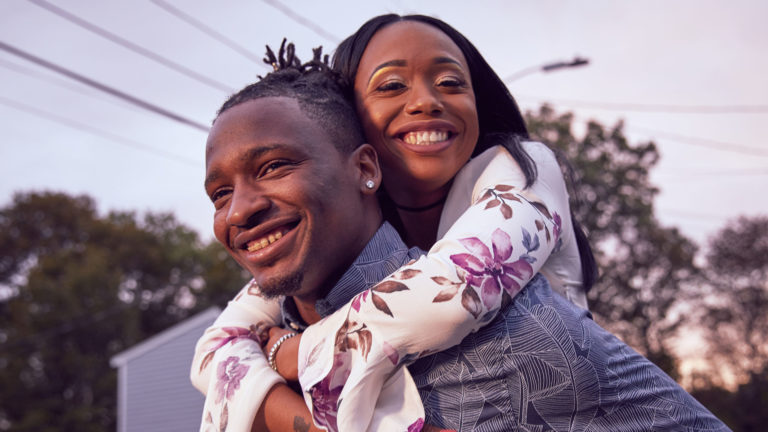 A young couple holding each other outside
